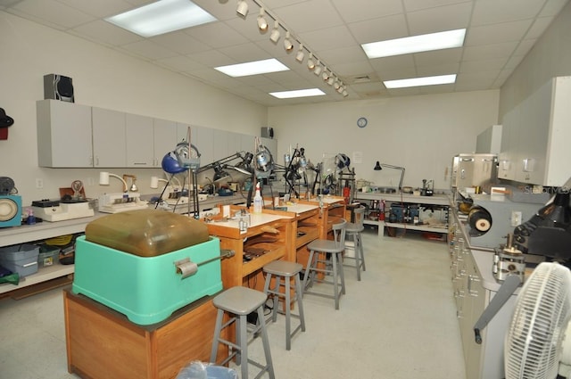 misc room with a workshop area, track lighting, and a paneled ceiling