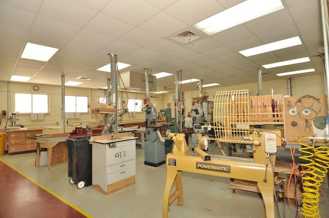 misc room featuring a paneled ceiling, visible vents, concrete floors, and a workshop area