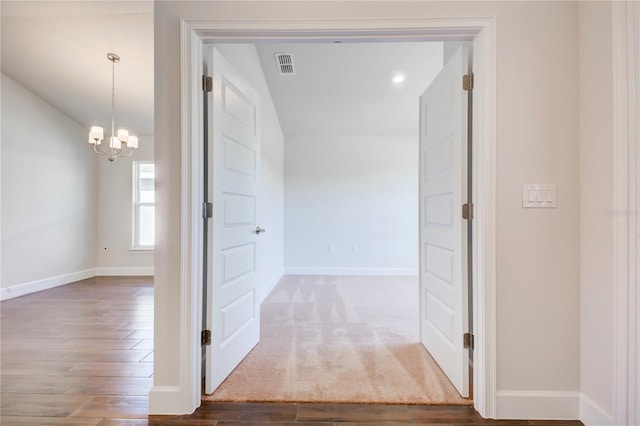 hall featuring a notable chandelier and dark wood-type flooring