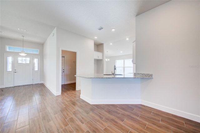 kitchen featuring kitchen peninsula, white cabinetry, hanging light fixtures, and a healthy amount of sunlight