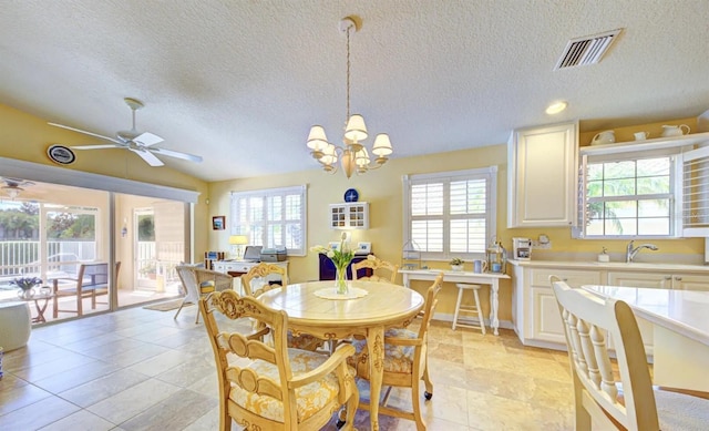 dining space featuring lofted ceiling, sink, ceiling fan with notable chandelier, and a textured ceiling