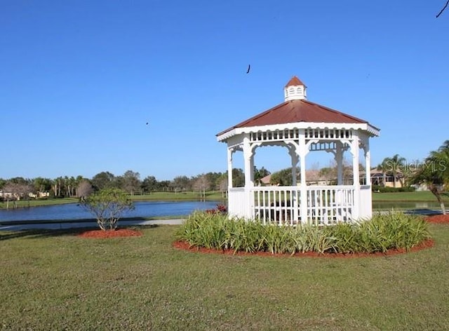 view of property's community with a gazebo, a water view, and a lawn