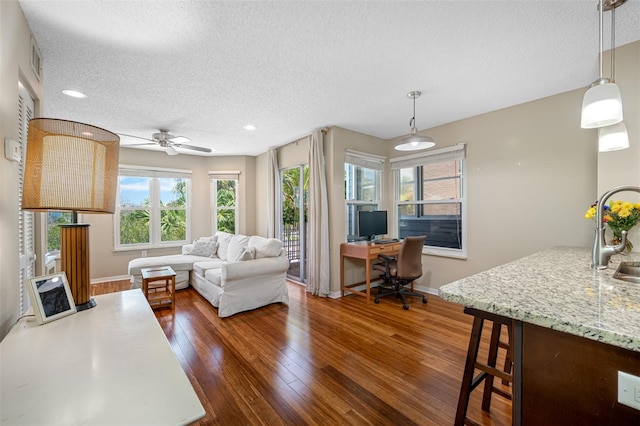 living room with sink, ceiling fan, dark hardwood / wood-style flooring, and a textured ceiling