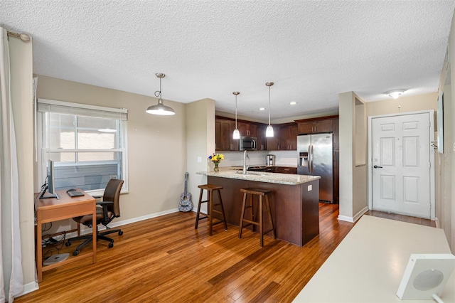 kitchen with wood-type flooring, stainless steel appliances, kitchen peninsula, and sink