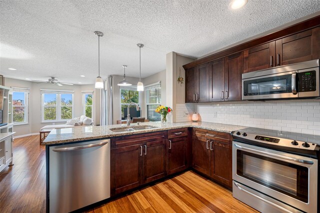 kitchen featuring light hardwood / wood-style flooring, kitchen peninsula, sink, and appliances with stainless steel finishes