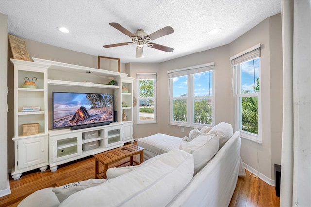 living room featuring a textured ceiling, ceiling fan, and hardwood / wood-style flooring