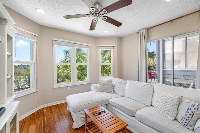 living room with a wealth of natural light, ceiling fan, hardwood / wood-style floors, and a textured ceiling