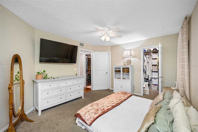 carpeted bedroom featuring a textured ceiling, a walk in closet, ceiling fan, and a closet