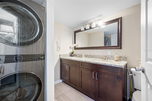 bathroom with tile patterned floors, vanity, toilet, and stacked washer / drying machine