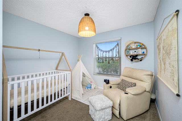 bedroom with a crib, dark colored carpet, and a textured ceiling