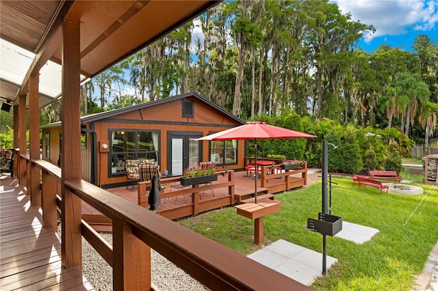 wooden deck with an outbuilding, a yard, and a fire pit