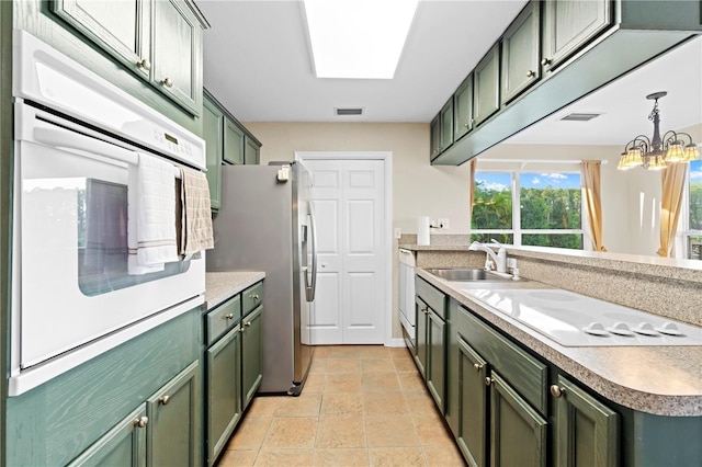 kitchen featuring sink, green cabinetry, decorative light fixtures, stainless steel fridge with ice dispenser, and oven