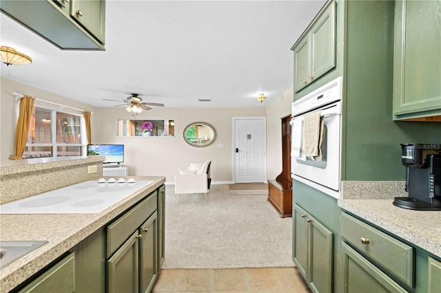 kitchen featuring ceiling fan, green cabinets, light colored carpet, and white appliances