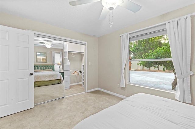 bedroom featuring multiple windows, ceiling fan, light carpet, and a closet