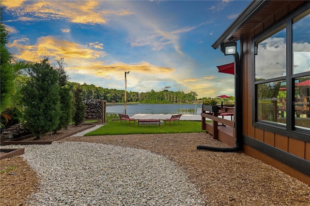 yard at dusk featuring a water view