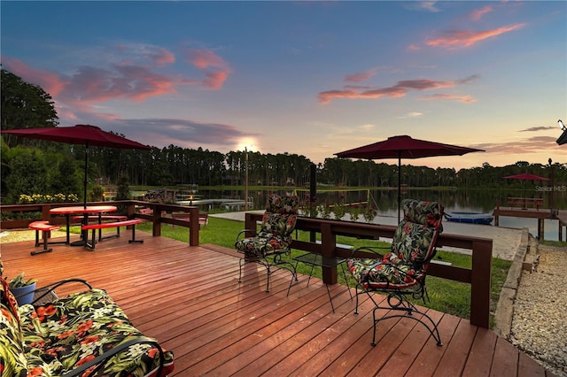 deck at dusk featuring a water view