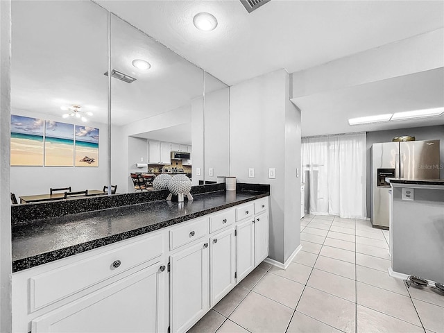 kitchen featuring white cabinets, stainless steel appliances, light tile patterned flooring, and dark stone countertops