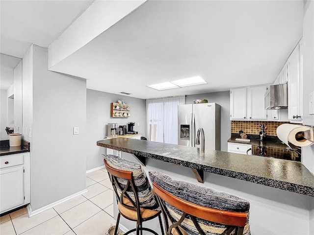 kitchen with white cabinets, light tile patterned flooring, a kitchen bar, and appliances with stainless steel finishes