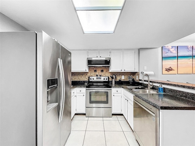 kitchen with light tile patterned flooring, white cabinetry, appliances with stainless steel finishes, backsplash, and sink