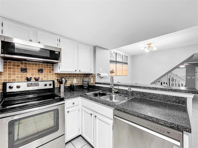 kitchen with light tile patterned flooring, white cabinetry, sink, appliances with stainless steel finishes, and backsplash