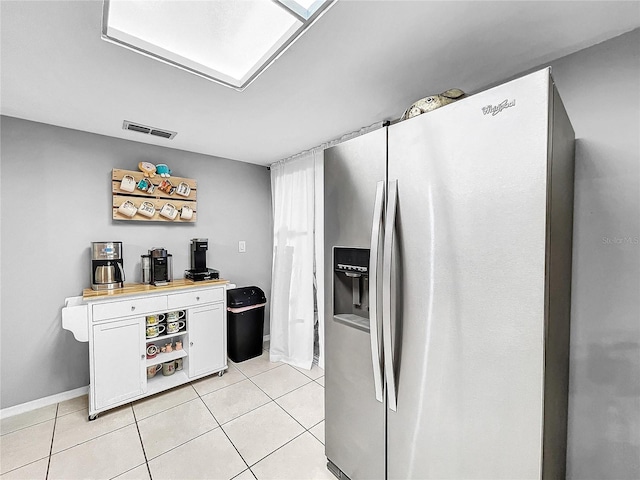 kitchen featuring white cabinets, light tile patterned floors, and stainless steel fridge