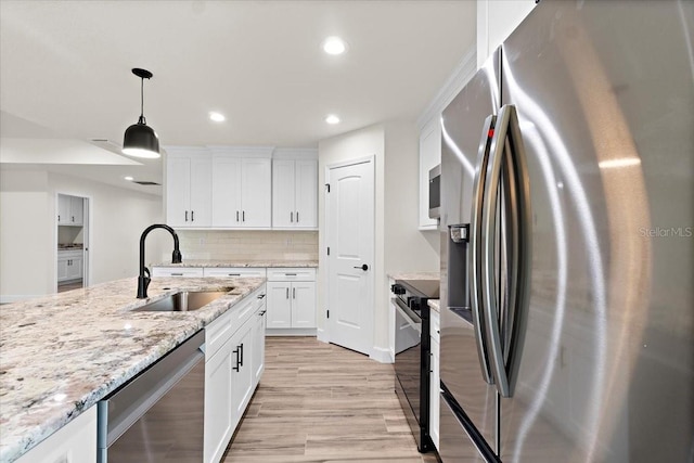 kitchen with decorative light fixtures, white cabinets, sink, and stainless steel appliances