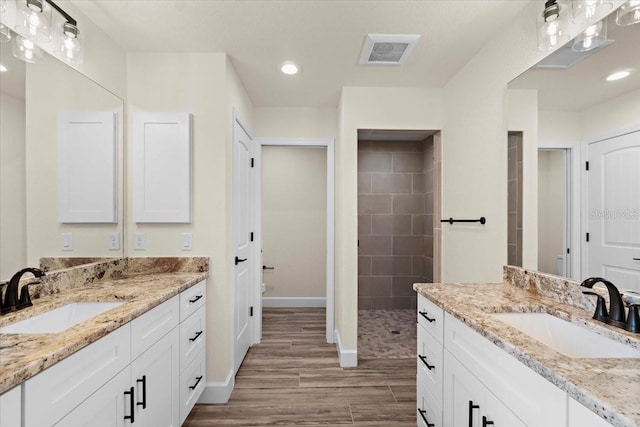 bathroom featuring vanity, hardwood / wood-style flooring, and a tile shower