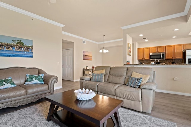 living room featuring ornamental molding, light hardwood / wood-style floors, and a notable chandelier