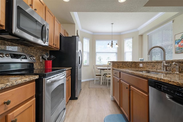 kitchen featuring stone countertops, sink, ornamental molding, stainless steel appliances, and light hardwood / wood-style flooring