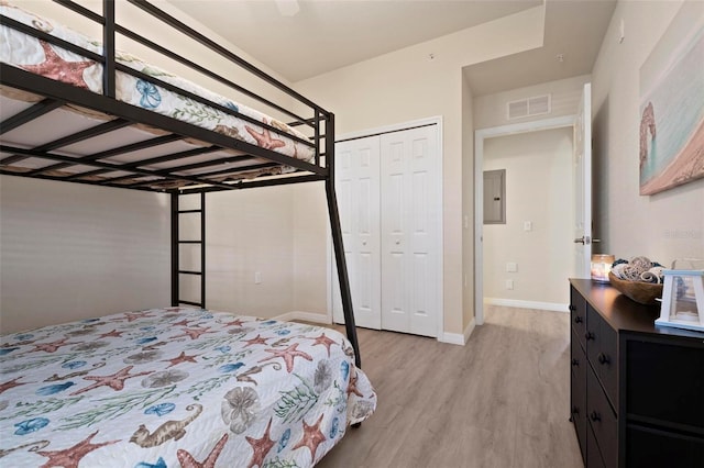 bedroom with light hardwood / wood-style flooring, electric panel, and a closet