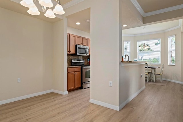 kitchen featuring pendant lighting, stainless steel appliances, decorative backsplash, a chandelier, and light wood-type flooring