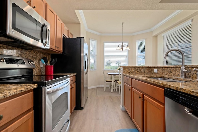 kitchen featuring sink, dark stone countertops, light hardwood / wood-style floors, stainless steel appliances, and crown molding