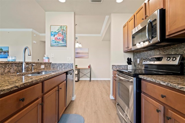 kitchen featuring sink, crown molding, appliances with stainless steel finishes, dark stone countertops, and light hardwood / wood-style floors