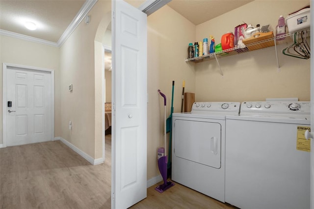 clothes washing area with crown molding, separate washer and dryer, a textured ceiling, and light wood-type flooring