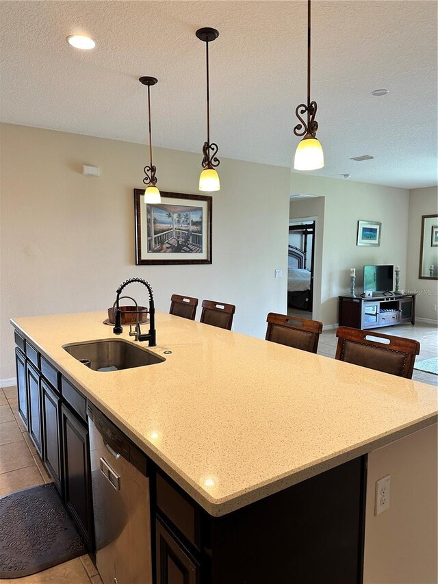 kitchen with light tile patterned flooring, stainless steel dishwasher, hanging light fixtures, and sink