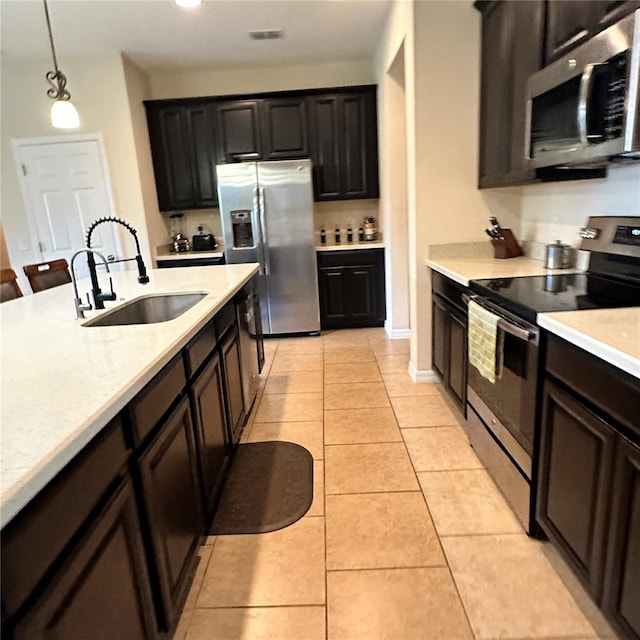 kitchen featuring a breakfast bar, stainless steel appliances, sink, hanging light fixtures, and light tile patterned flooring