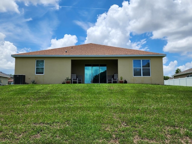 back of property featuring cooling unit and a lawn