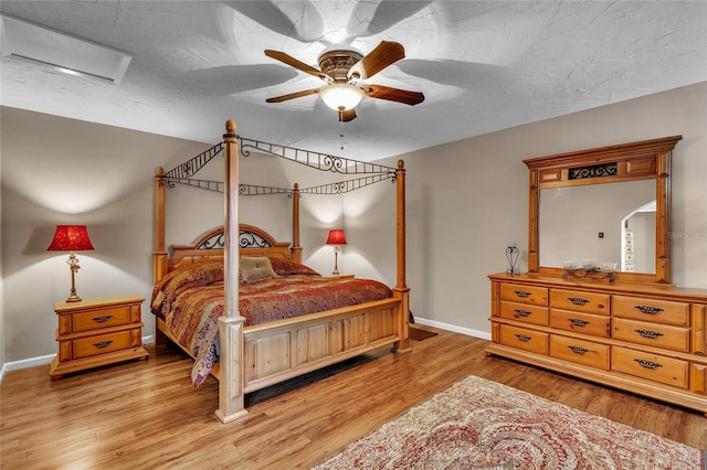 bedroom with a textured ceiling, light hardwood / wood-style floors, and ceiling fan