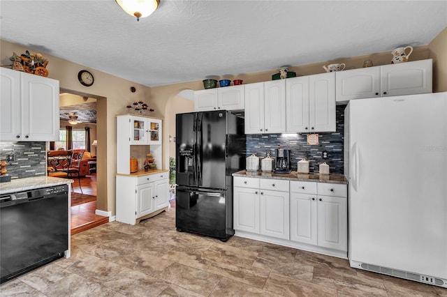 kitchen with white cabinetry, dark stone counters, and black appliances