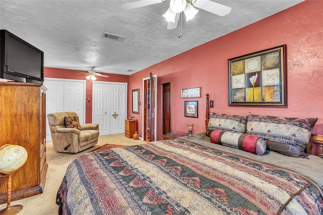 bedroom with multiple closets, ceiling fan, light colored carpet, and a textured ceiling