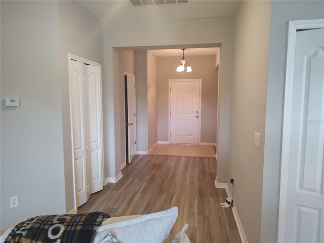 hall featuring light hardwood / wood-style floors and a chandelier