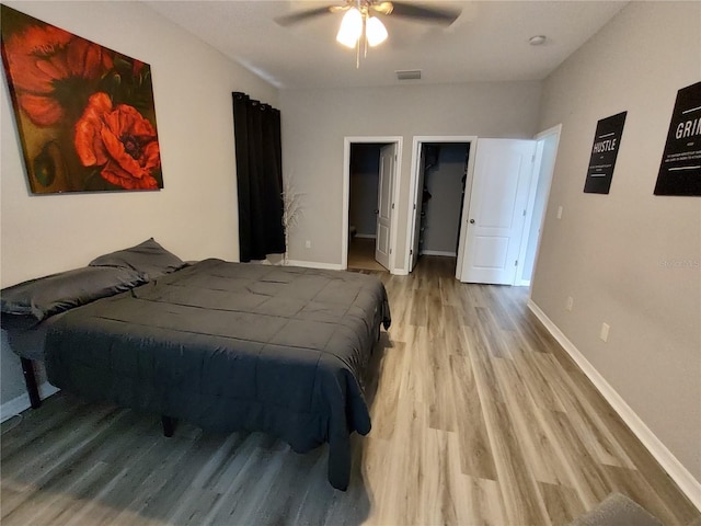 bedroom with light hardwood / wood-style floors, a spacious closet, and ceiling fan