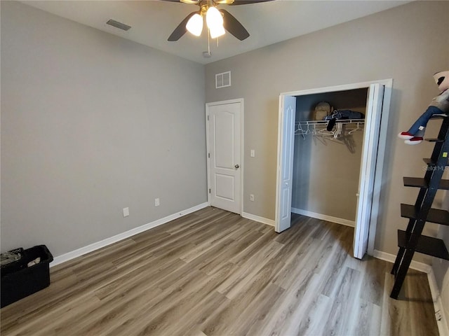 unfurnished bedroom with hardwood / wood-style floors, ceiling fan, and a closet