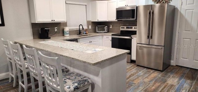 kitchen with white cabinetry, sink, stainless steel appliances, and light stone counters