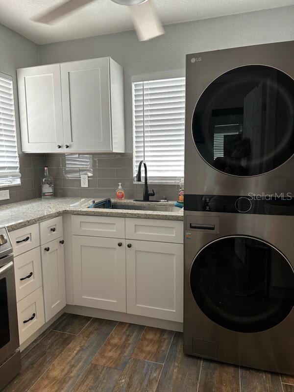 kitchen with stainless steel range with electric stovetop, white cabinetry, and stacked washer and clothes dryer