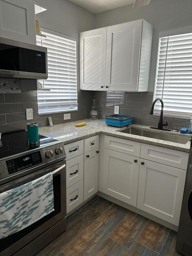 kitchen featuring sink, tasteful backsplash, light stone counters, white cabinets, and appliances with stainless steel finishes