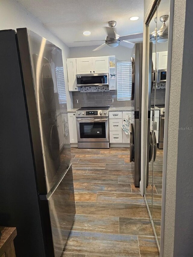 kitchen featuring decorative backsplash, a textured ceiling, stainless steel appliances, ceiling fan, and white cabinets