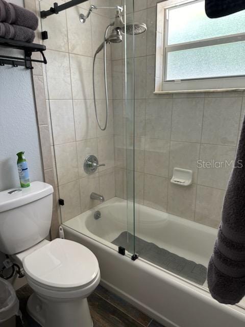 bathroom with shower / bath combination with glass door, hardwood / wood-style floors, and toilet