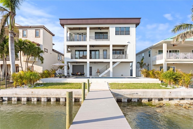 back of house featuring stucco siding, a water view, a patio area, ceiling fan, and stairs