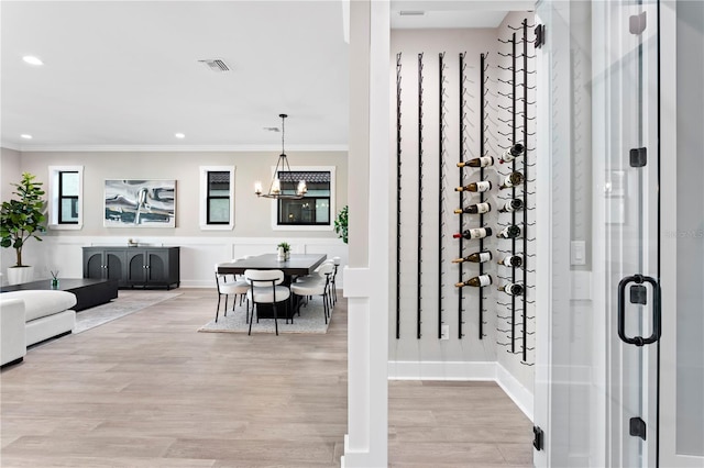 wine cellar with light wood-type flooring, visible vents, crown molding, and recessed lighting